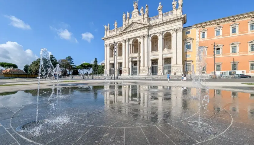 La fontaine devant la cathédrale de Rome, Saint-Jean-de-Latran, reflète le ciel bleu et l'architecture imposante.