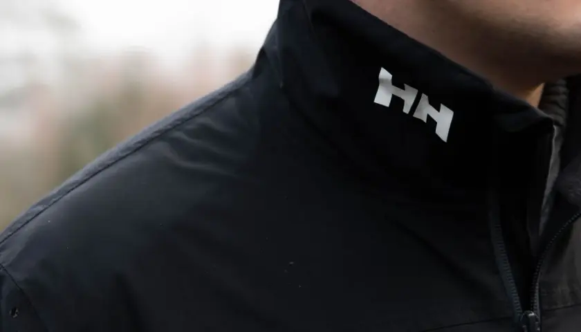 Czarna kurtka z białym logo HH. Helly Hansen to firma znana z odzieży outdoorowej i żeglarskiej.