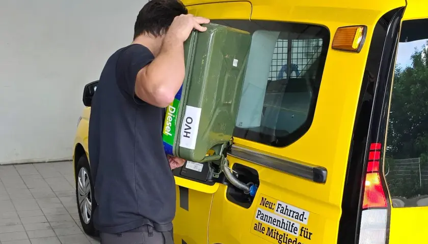 Uomo versa diesel paraffinico da tanica verde in un furgone giallo.
