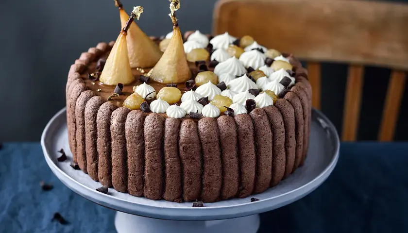 Charlotte poire chocolat, un gâteau élégant avec des poires pochées dorées, de la crème fouettée et des éclats de chocolat.