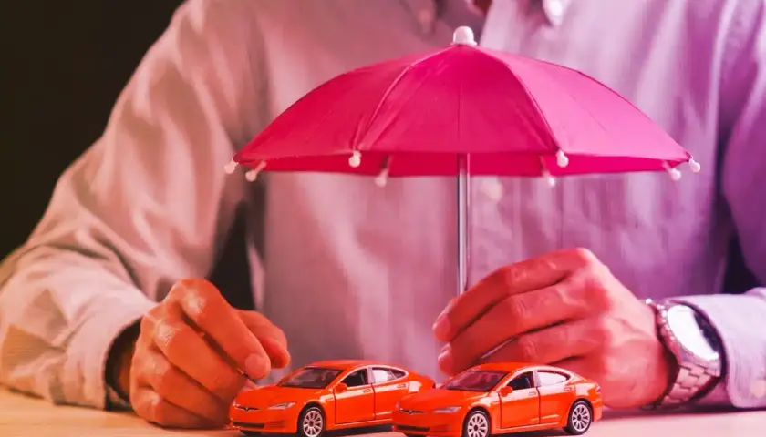 Due macchinine arancioni sotto un ombrello rosa. Capire la **legge Bersani assicurazione come funziona** è fondamentale per proteggere il tuo veicolo.