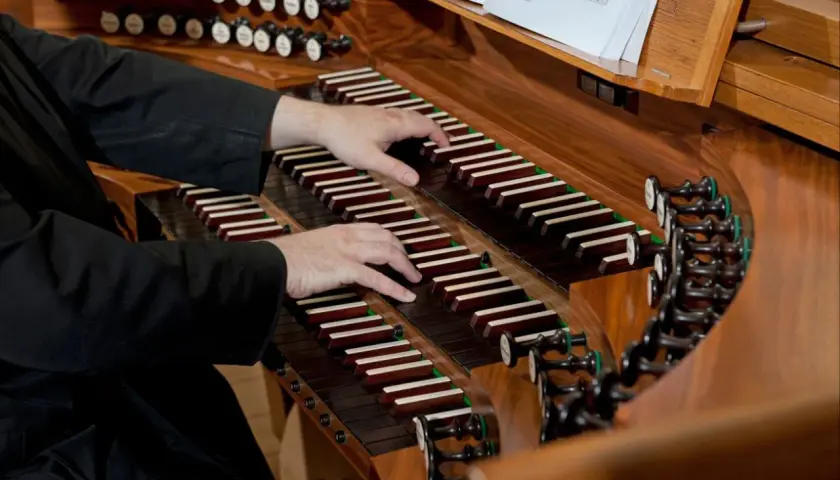 Dłonie organisty grają na klawiaturze. Zastanawiasz się, ile zarabia organista za mszę?