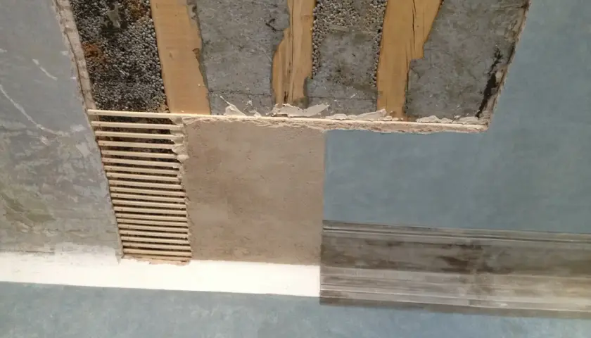 Soffitto in fase di ristrutturazione, con travi a vista e intonaco parzialmente rimosso. Si vede come rasare un soffitto rovinato, con listelli di legno e nuovo intonaco.