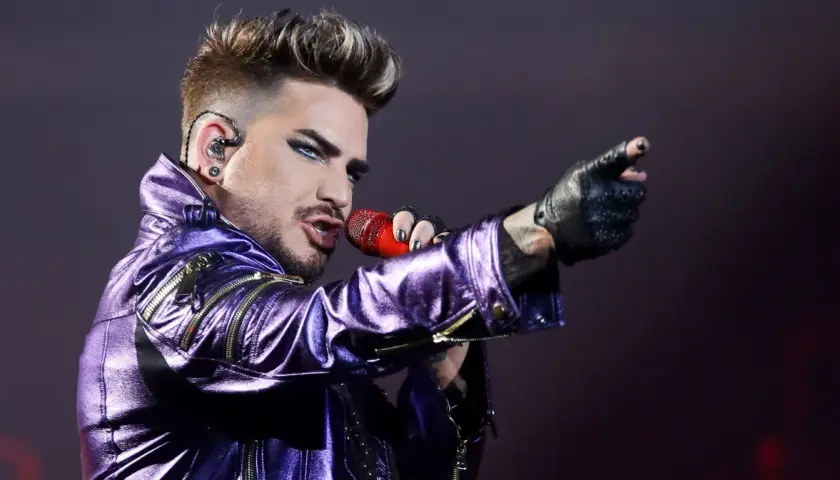 Adam Lambert w błyszczącej, fioletowej kurtce śpiewa z mikrofonem, wskazując palcem. To jakby Queen powrócił na scenę z nową energią.