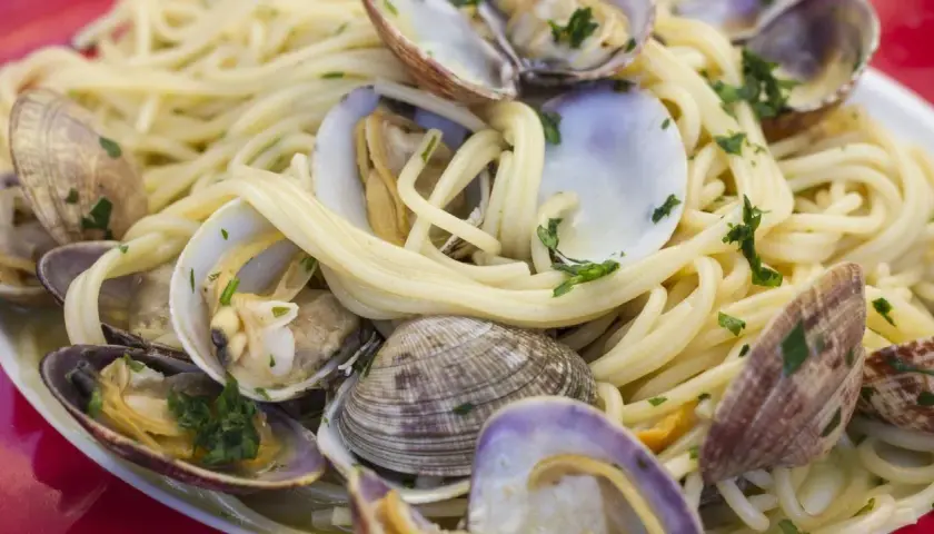 Un piatto invitante di spaghetti alle vongole, con pasta dorata e molluschi freschi, guarnito con prezzemolo tritato.