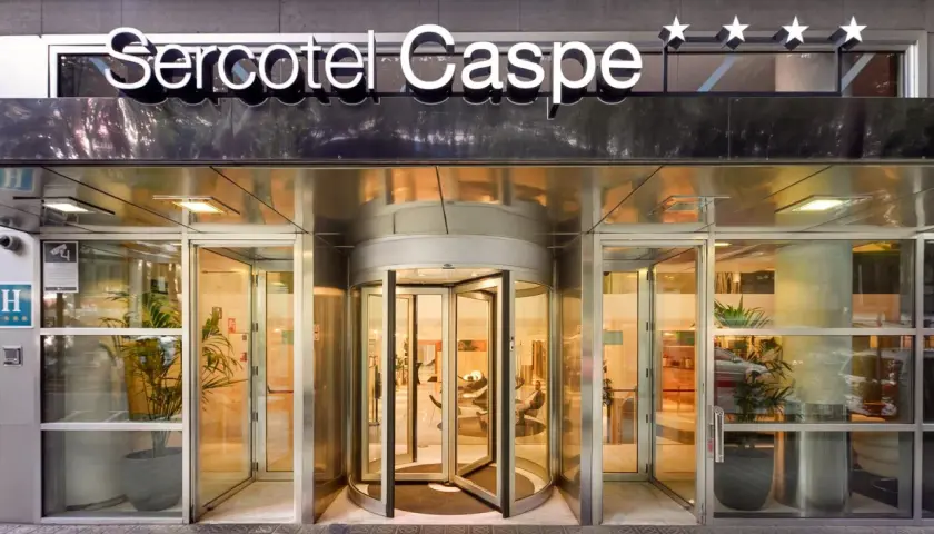 Entrada principal del Sercotel Caspe, con puerta giratoria y letrero luminoso.