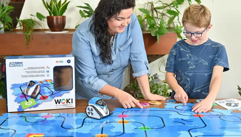 Mama i syn bawią się robotem WOKI, ucząc się kodowania dla 6 latka. Kolorowe klocki tworzą labirynt.