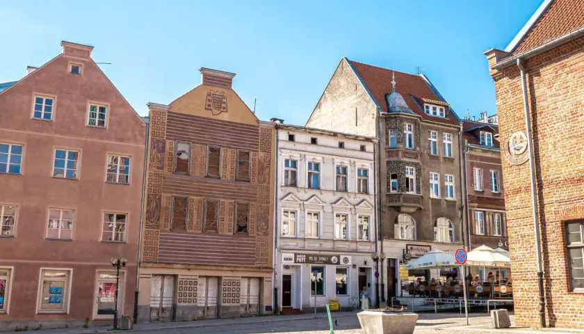 Kamienice Starego Miasta w Olsztynie z widocznym placem i zieloną hulajnogą.