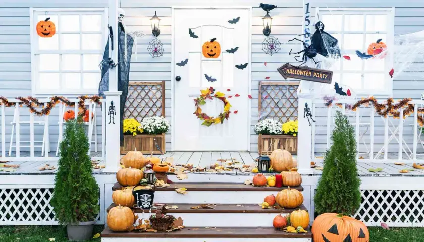 Porche decorado para Halloween con calabazas, telarañas, murciélagos y un esqueleto.
