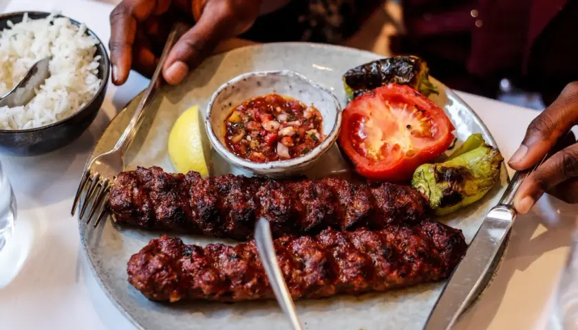 Dwa soczyste, grillowane kebaby na talerzu z ryżem, pomidorem, papryką i sosem. Tak wygląda pyszny kebab!