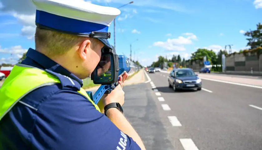 Policjant mierzy prędkość pojazdu, aby ustalić taryfikator punktów karnych.