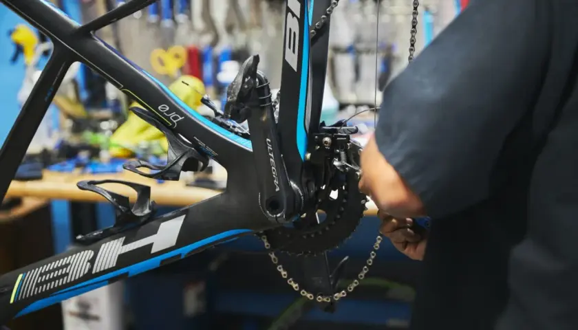 Mechanik dokonuje regulacji przedniej przerzutki w rowerze szosowym. Widać korbę Ultegra i ramę BH.