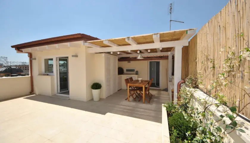 Un terrazzo sul tetto con tavolo in legno, pergola di bambù e vista sulla città. Ideale per cene all'aperto.