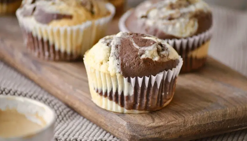 Saftige Marmor Muffins mit einem Swirl aus hellem und dunklem Teig, serviert auf einem Holzbrett.