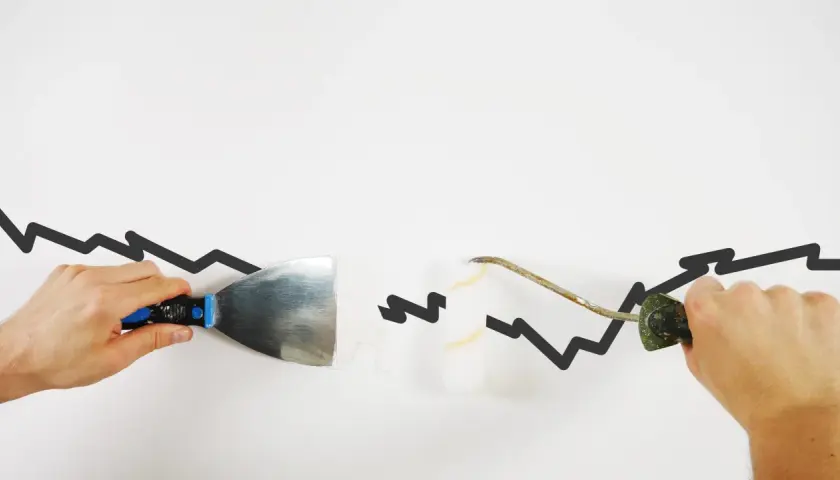 Hände reparieren mit Spachtel und Rolle eine gezackte Linie, die wie **risse in der wand** aussieht.