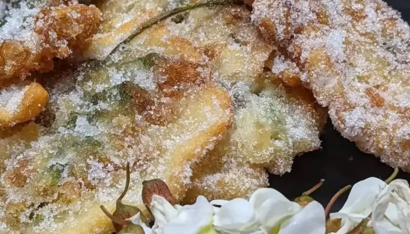 Délicieux beignets d'acacia, croustillants et saupoudrés de sucre, accompagnés de fleurs blanches.