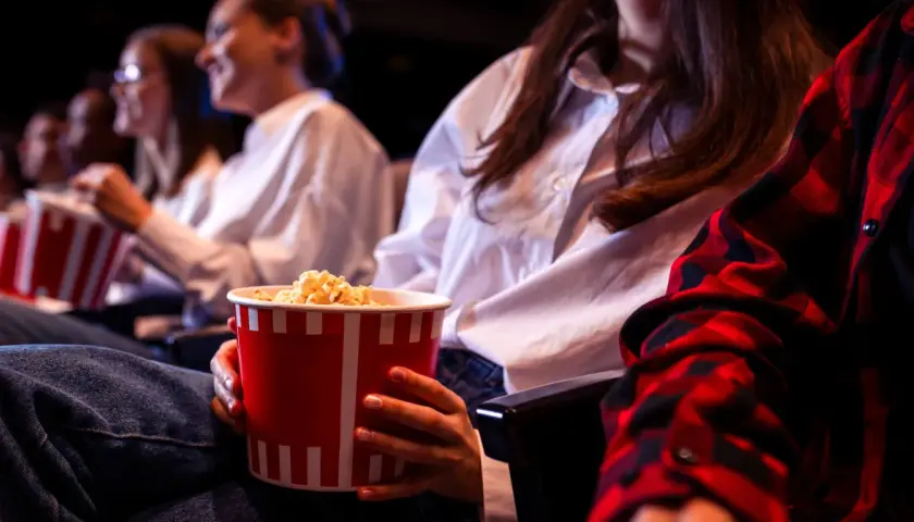 Ludzie w kinie jedzą popcorn. Zastanawiasz się, ile kosztują nachosy w kinie?