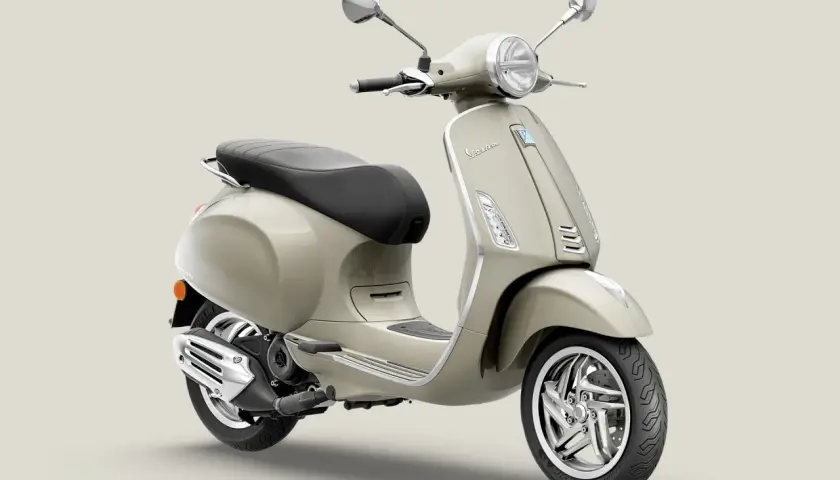 Vespa Primavera 50 color arena, con asiento negro y detalles cromados. Ideal para paseos urbanos.