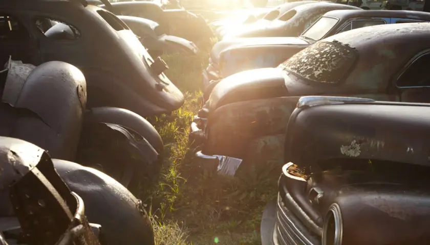 Rottami d'auto d'epoca al tramonto. Chissà quanto costa rottamare un'auto così, tra ruggine e ricordi.