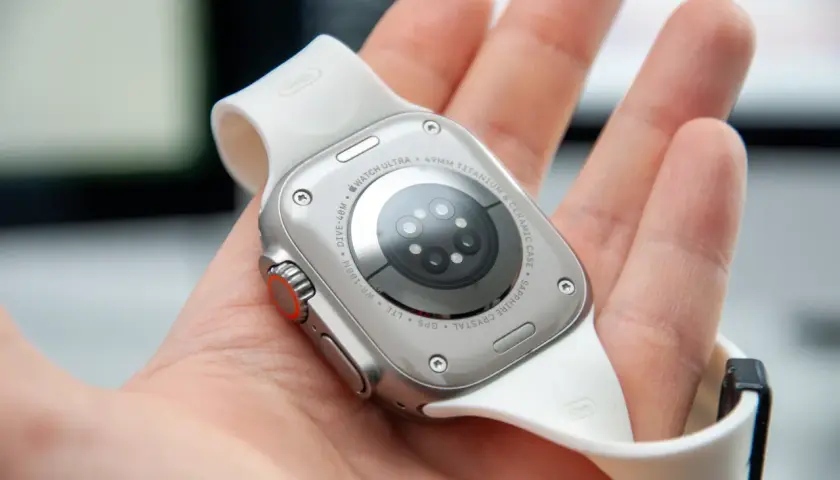 Naprawa smartwatcha Apple Watch Ultra. Widok na tył zegarka z białym paskiem, trzymanego w dłoni.