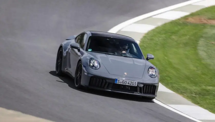 Un'auto sportiva ibrida grigia sfreccia su una pista, con il guidatore concentrato.