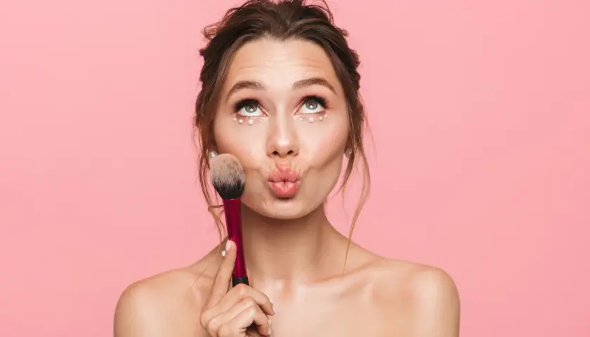 Jeune fille avec un maquillage simple et des perles sous les yeux, tenant un pinceau. Idéal pour un maquillage simple pour jeune fille.