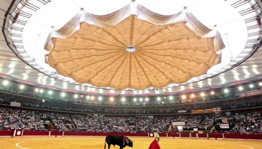 Vista del ruedo y los asientos de la plaza de toros de Zaragoza, con un toro y un torero en la arena, bajo una gran cubierta.
