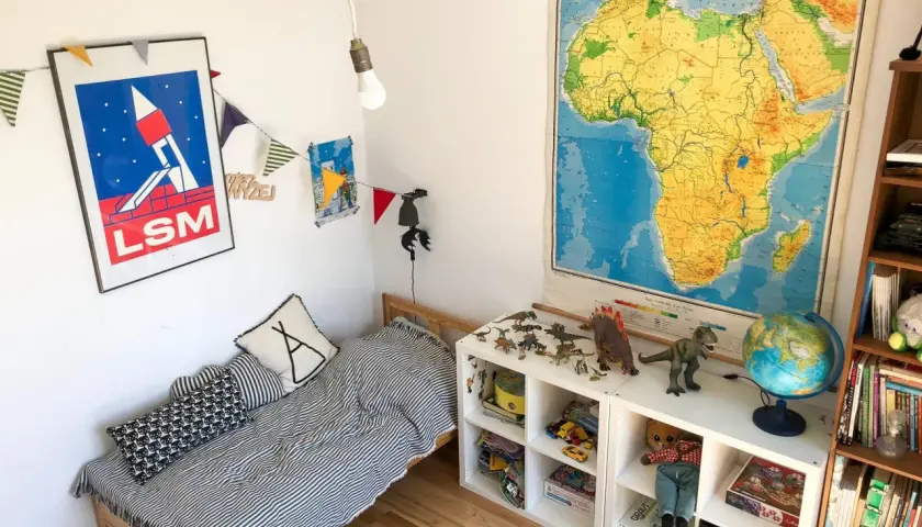 Pokój dziecka po metamorfozie: łóżko w paski, dinozaury i mapa Afryki.