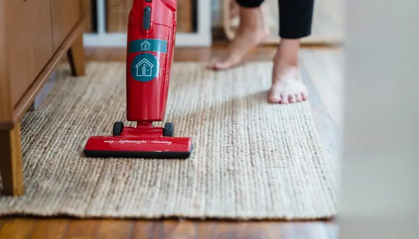 Czerwony odkurzacz Electrolux na dywanie. Gdzie jest bezpiecznik? Może w uchwycie, gdzie są przyciski?