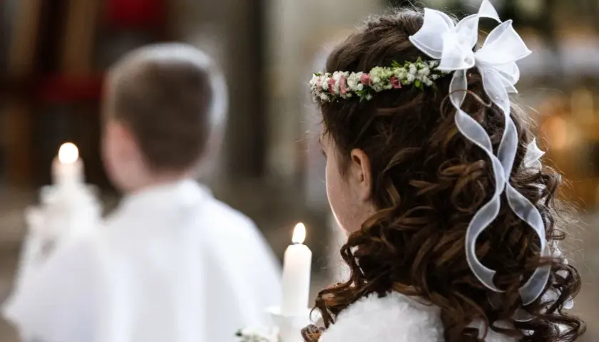 Dziewczynka z wiankiem i wstążkami we włosach trzyma świecę. Obok niej chłopiec. To ważny dzień, zastanawiasz się, ile trwa biały tydzień?