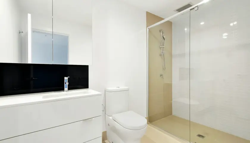 Mampara de ducha de cristal con medidas adecuadas para que no salga el agua. Baño moderno con lavabo, inodoro y ducha.