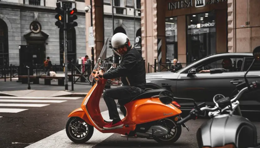 Uomo su scooter 150 con patente B, fermo al semaforo in città.