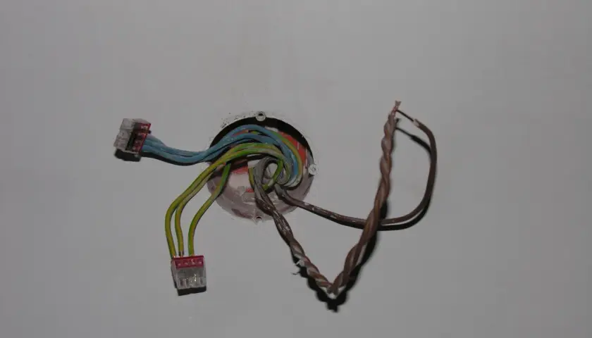 Instalacja elektryczna z kolorowymi przewodami w puszce, gotowa do podłączenia, aby zrobić dodatkowy punkt świetlny.
