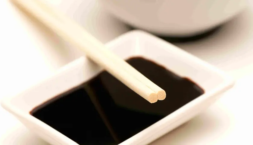 Bacchette appoggiate su una ciotolina di salsa di soia, un condimento che, se consumato in eccesso, può causare diarrea.
