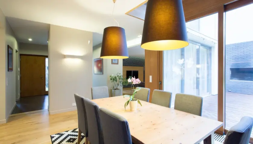 Nowoczesna jadalnia z drewnianym stołem i szarymi krzesłami. To przykład, jak home staging co to znaczy – tworzy przytulną atmosferę.