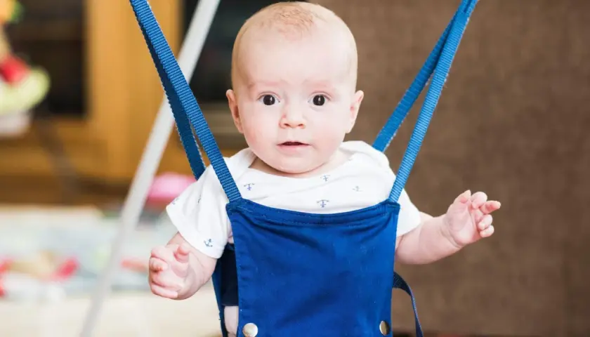 Uśmiechnięty bobas w niebieskim skoczku dla dzieci, wspierający rozwój ruchowy i fizjoterapię.