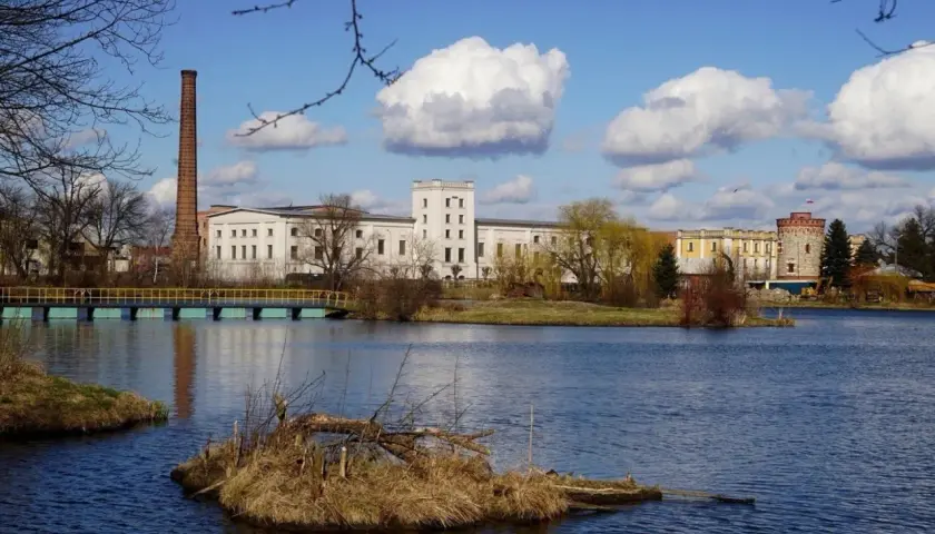 Nad jeziorem w Kazimierzu Wielkim, z ceglanym kominem i wieżą, rozciąga się kompleks budynków. Atrakcje tego miejsca przyciągają wzrok.
