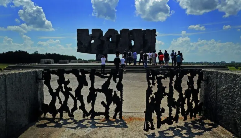 Brama pamięci na terenie byłego obozu Majdanek. Grupa ludzi zwiedza miejsce pamięci.