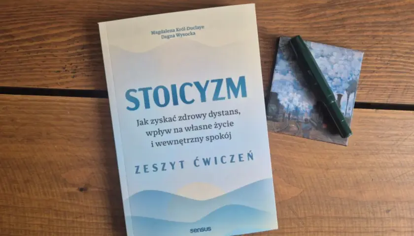 Książki o stoicyzmie na drewnianym stole. Zeszyt ćwiczeń "Stoicyzm" zachęca do zdrowego dystansu i wewnętrznego spokoju.