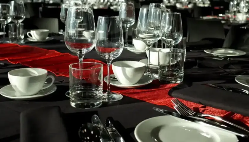 Elegancko nakryty stół na stypę, z kieliszkami do wina i szklankami, sugeruje, że alkohol może być serwowany.