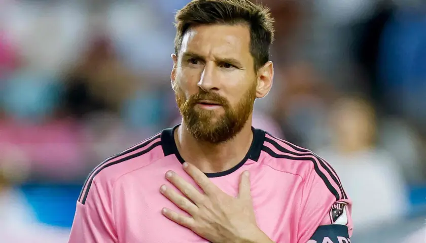 Piłkarz w różowej koszulce z opaską kapitana, z ręką na sercu. Plotki o tym, że messi nie żyje, są fałszywe.