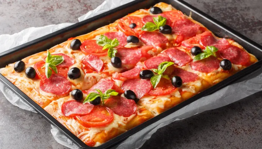 Chrupiąca pizza z ciasta francuskiego z salami, pomidorami, oliwkami i bazylią, prosto z blachy.
