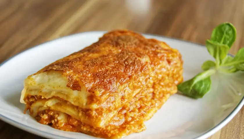 Pyszna, zapieczona lasagne z mięsem mielonym na talerzu. Idealna na prosty obiad.