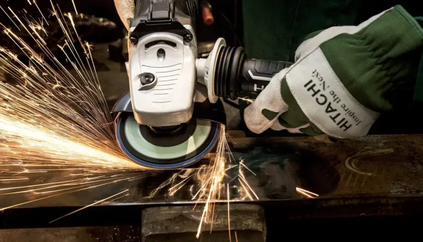 Rękawica Hitachi z tarczą szlifierską generuje iskry, pokazując siłę tarcia statycznego podczas pracy z metalem.