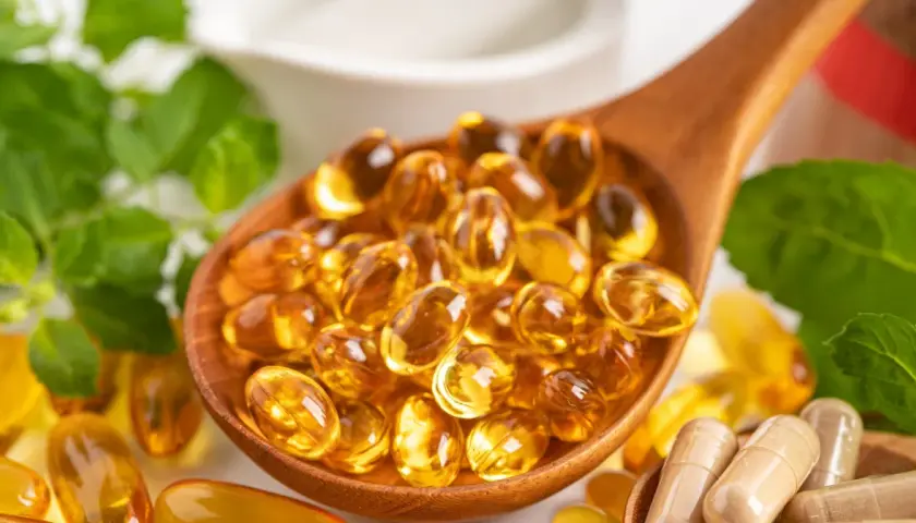 Łyżka pełna kapsułek z omega 3. Kwasy te wspierają serce, mózg i wzrok.