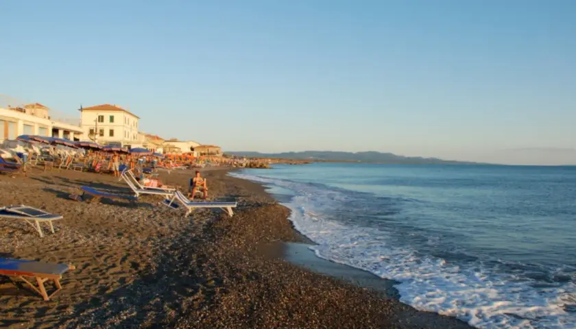 Plage de Cecina, Italie. Chaises longues et parasols sur le sable, mer calme sous un ciel bleu.