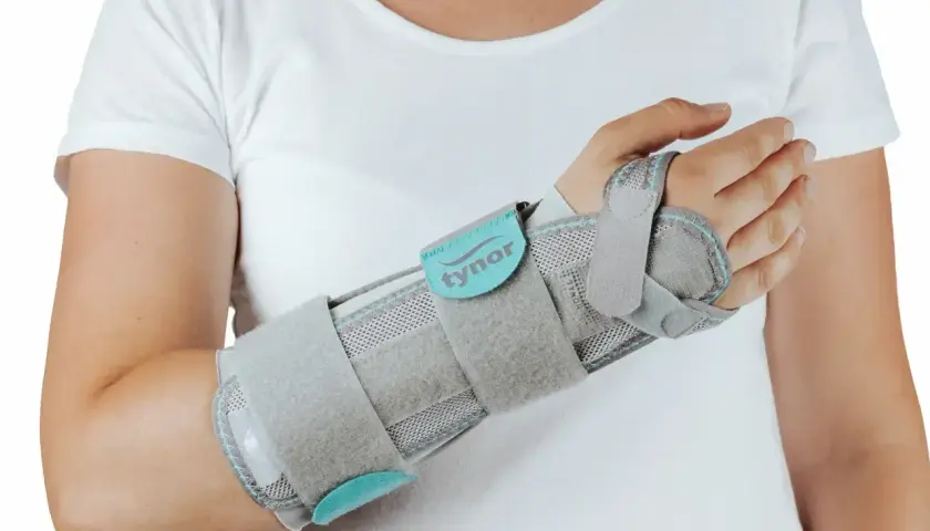 Szara orteza na nadgarstek, która zapewnia stabilizację, lepsza niż gips.