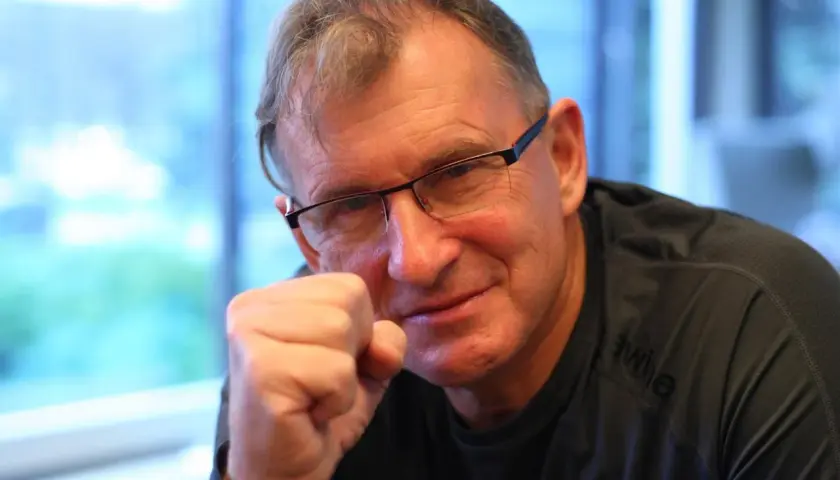 Jerzy Górski w okularach, opierający pięść o policzek, uśmiecha się.