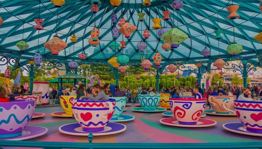 Kolorowa karuzela w kształcie filiżanek w Disneylandzie w Europie, z mnóstwem wiszących lampionów.