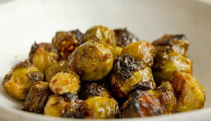 Cavolini di Bruxelles al forno, croccanti e dorati, serviti in una ciotola. Un contorno delizioso e salutare.